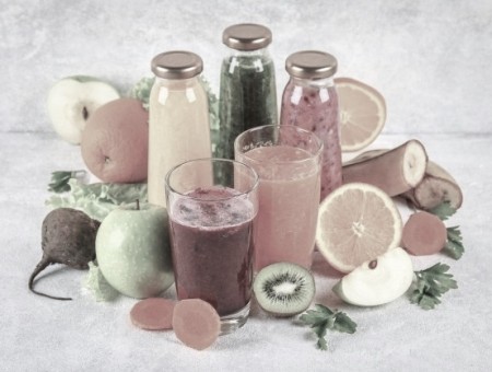 batidos-verdes-amarillos-morados-botellas-grosella-perejil-manzana-kiwi-naranja-sobre-mesa-gris_71756-552.jpg